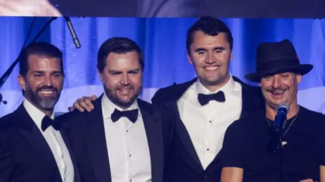 Charlie Kirk, centre, poses for photo with JD Vance and Donald Trump Jr. They are all wearing black and white tuxedos.