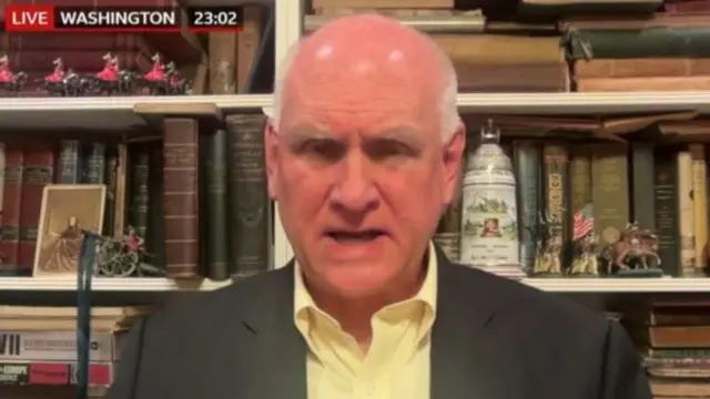 Jim Townsend speaks on a Zoom call with his bookshelf in the background
