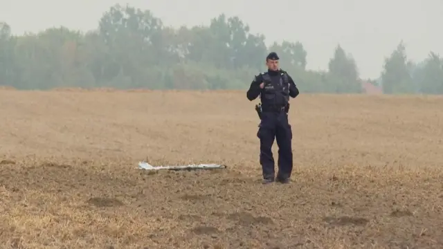 A Polish police officer stands near a UAV fragment
