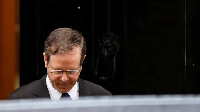 Herzog leaves No 10 wearing a suit and glasses.