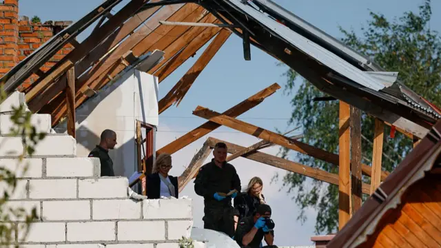 Four people visible in the wrecked roof of a home.