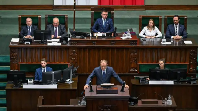 Polish Prime Minister Donald Tusk speaks from a lectern in parliament