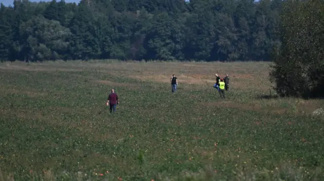 Men search a field in Krzywowierzba-Kolonia, in Poland's eastern Lublin province