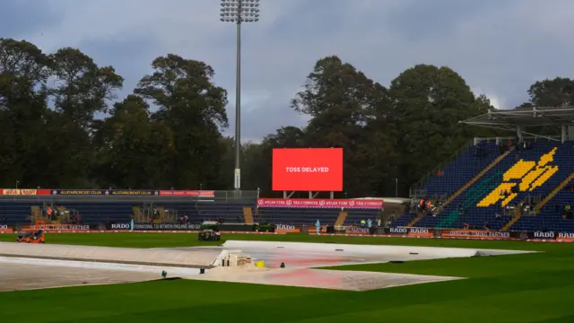 Toss delayed wording on the screen with covers on the pitch