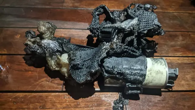 A charred cylindrical device with a burnt netting attached