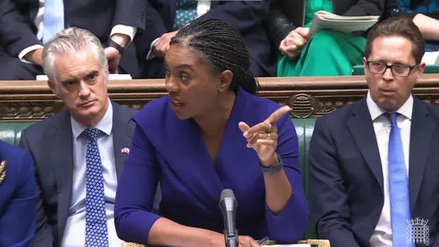 Conservative leader Kemi Badenoch wearing a blue dress and gesturing at the prime minister.