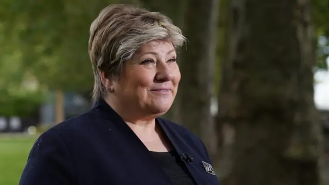 Woman wearing lapel mic smiles into distance