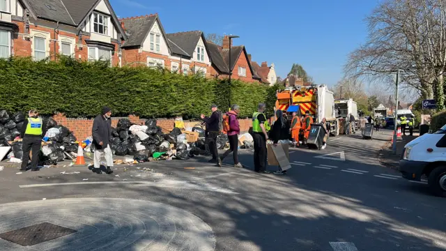People and police next to piles of rubbish on the street
