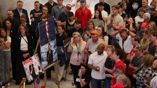 Wide shot of a crowd standing around easels with Kirk's photos