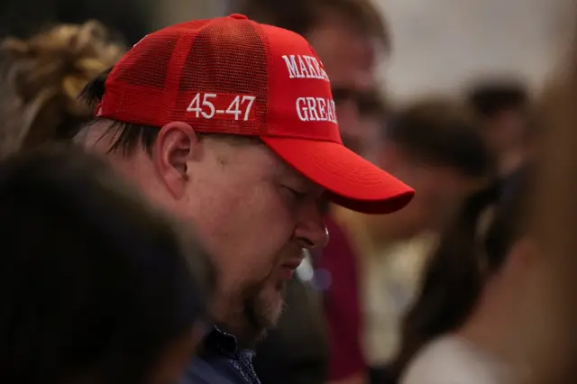 Side view of a man wearing a Make America Great Again hat closing his eyes
