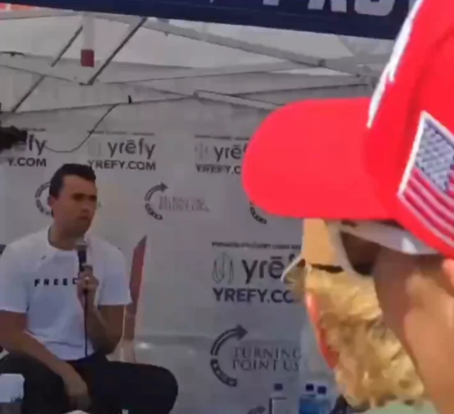 Kirk sitting underneath a marquee in front of a large crowd of people