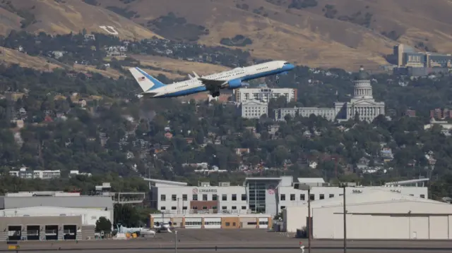 Air Force Two departs from Salt Lake City airport. City buildings are seen in the background.