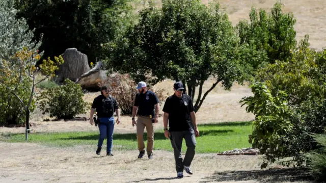 Law enforcement officers investigate a residential yard in a neighborhood near Utah Valley University