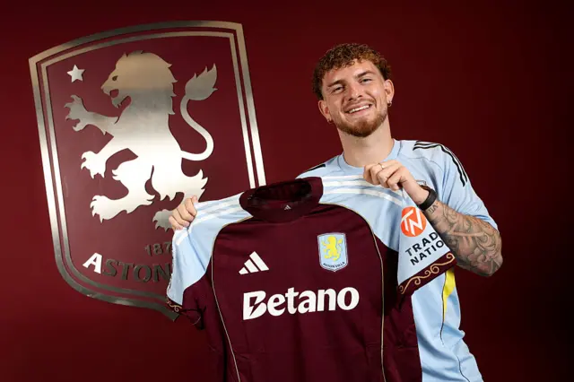 Harvey Elliott holding an Aston Villa shirt