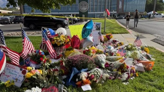 A pile of flowers and small US flags along with notes left in tribute to Kirk
