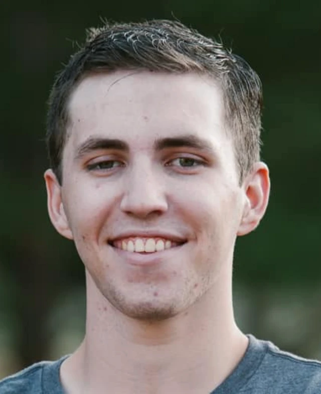 A picture of a man in a grey t-shirt looking at the camera and smiling