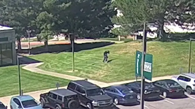 CCTV footage shows a man, wearing black clothes, running away from a building on grass.