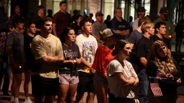 Several people gather at a vigil to remember Charlie Kirk
