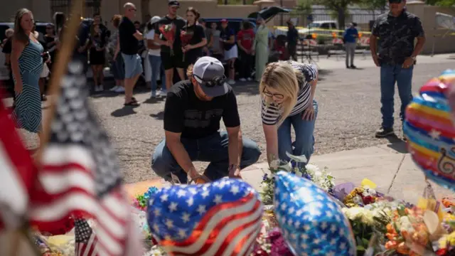 Two people place flowers on the ground after the fatal shooting of conservative activist Charlie Kirk, at the Turning Point USA headquarters in Phoenix, Arizona.