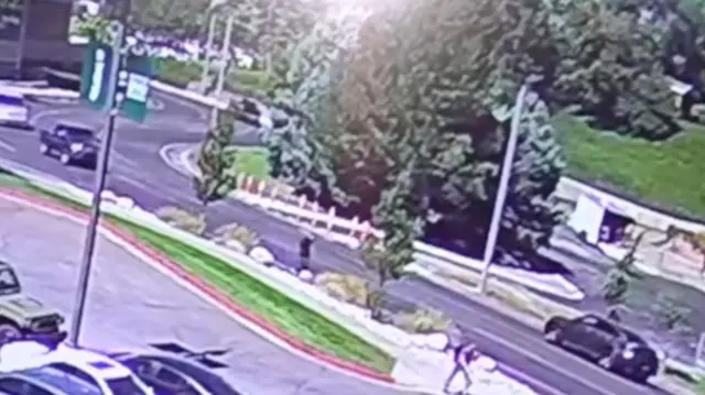 CCTV images show a car-park with the suspect, wearing a black t-shirt, about to cross the street.