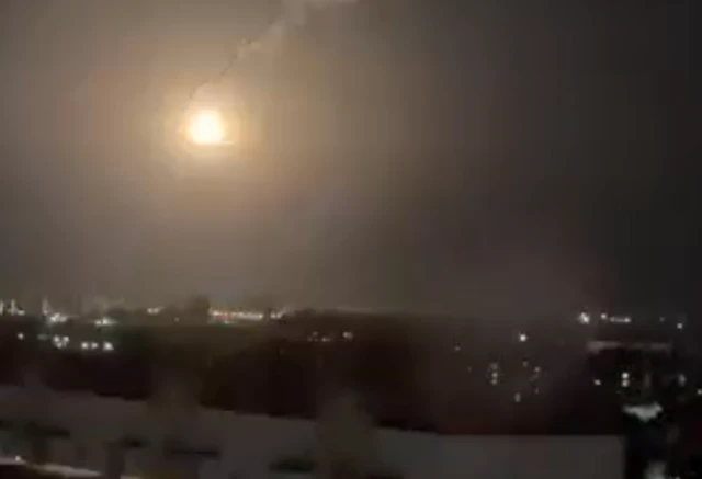A bright light in the sky over a dark city