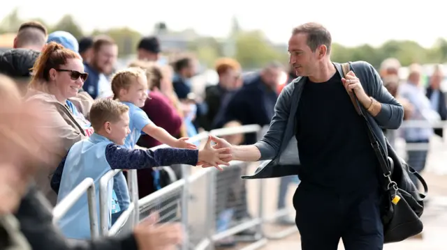 Frank Lampard high-fives a fan after arriving at the CBS Arena