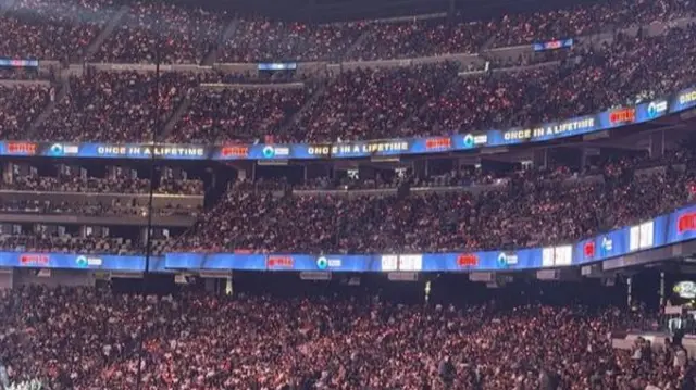 Packed out rafters in the Allegiant Stadium with fans all wearing LED bracelets which are illuminated red