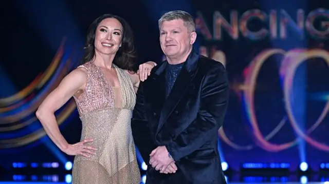 Ricky Hatton in a velvet suit next to a woman with a gold dress