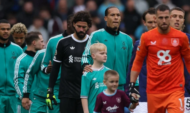 Liverpool's Virgil van Dijk and Liverpool's Alisson Becker walk onto the pitch with teammates