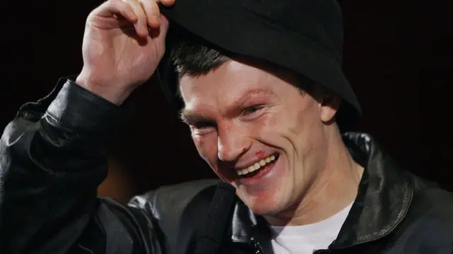 A man with a black hat and black jacket smiles