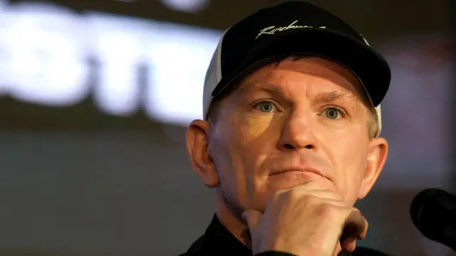 Ricky Hatton in a black hat with his hand on his chin