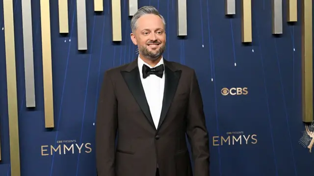 Nate Bargatze walks the carpet in a black tuxedo