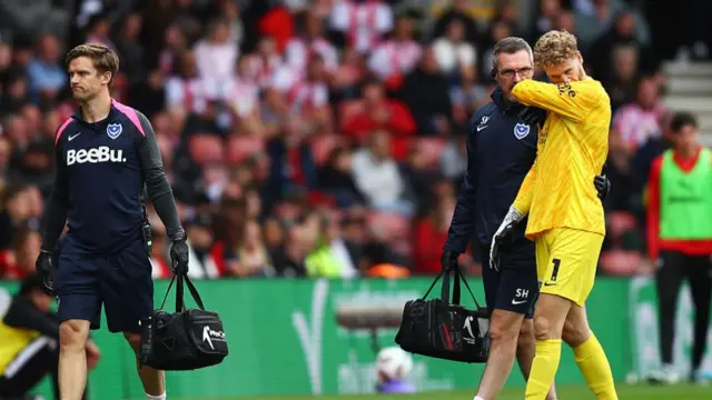Pompey goalkeeper Nicolas Schmid is forced to leave the game