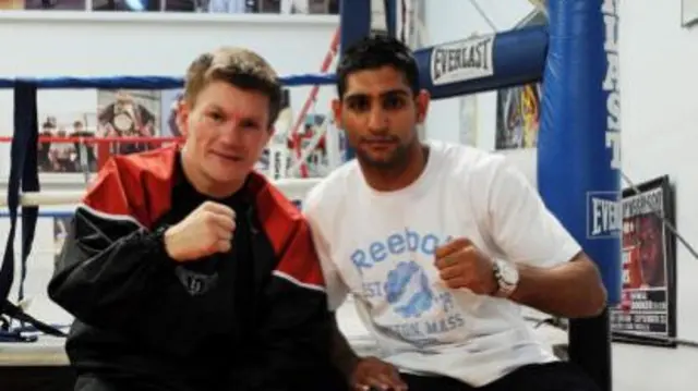 Ricky Hatton on the left in a red and black jacket, Amir Khan on the right in a white t-shirt