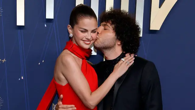 Selena Gomez in a red dress and Benny Blanco in a black suit