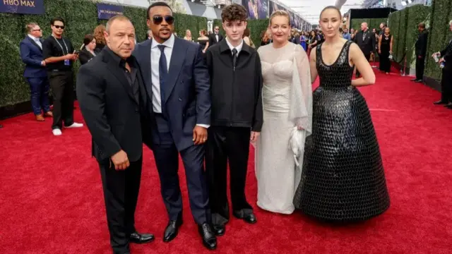 Actors Stephen Graham, Ashley Walters, Owen Cooper, Christine Tremarco and Erin Doherty attend The 77th Primetime Emmy Awards at Peacock Theater on September 14, 2025 in Los Angeles, California. Stephen is wearing an all black suit with a black shirt and open collar. Ashley wears a navy blue suit with a blue tie and light blue shirt. Owen wears a black jacket over a white shirt and tie and flared black trousers. Christine wears a long shimmering white dress with a mesh shawl. Erin wears a shiny black, bell shaped gown crafted with 3D embellished silk.