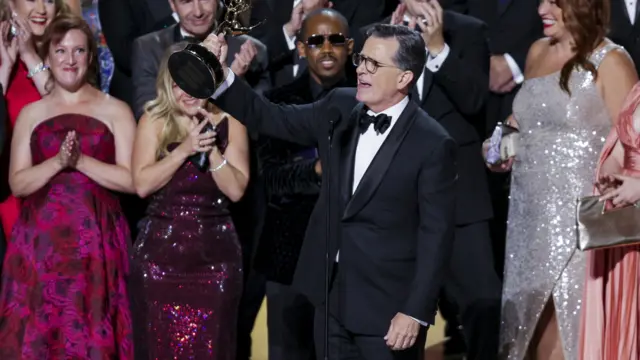 Louis Cato and Stephen Colbert , with cast and crew, accept the Emmy for Outstanding Talk Series for "The Late Show with Stephen Colbert" during the 77th annual Emmy Awards ceremony held at the Peacock Theater in Los Angeles
