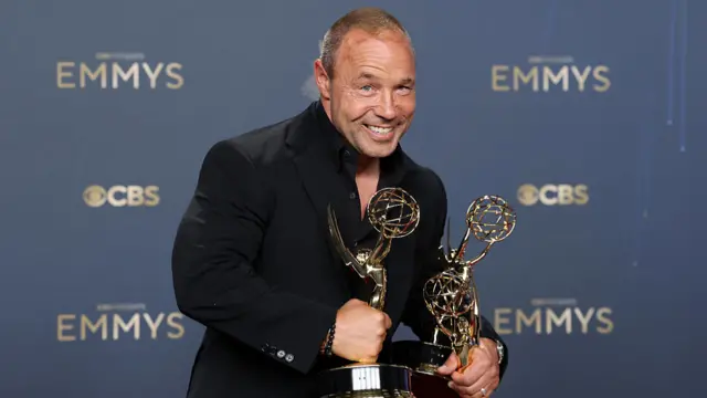 Actor Stephen Graham holding his Emmys trophies in the press room.
