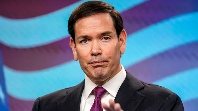 US Secretary of State Marc Rubio wearing a dark suit, white shirt and purple tie.