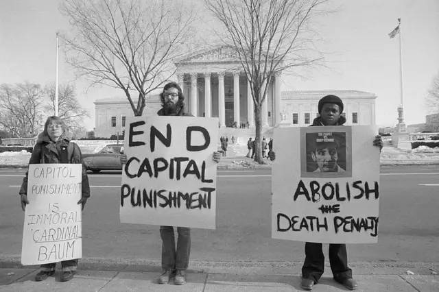 Anti-death penalty demonstrators express their views with large signs