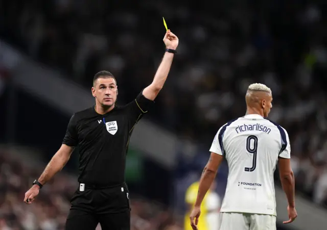Referee Rade Obrenovic shows Tottenham Hotspur's Richarlison a yellow card