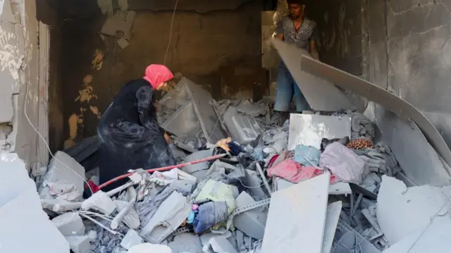 Palestinians search for victims at the site of an overnight Israeli strike on a house, in Gaza City