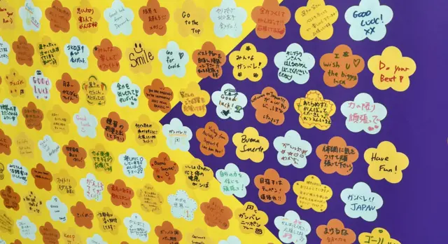 Worlds of inspiration sent by fans for athletes are shown on a wall outside the stadium