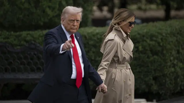 Donald and Melania Trump walking hand in hand - Trump points to the camera