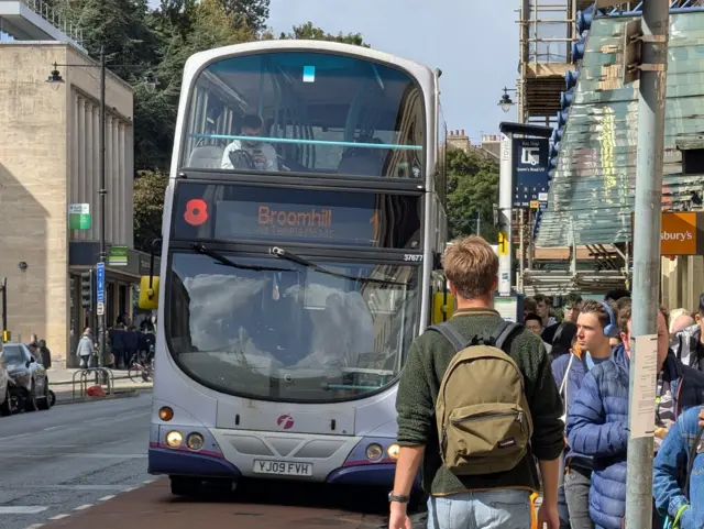 A large queue of people waiting to board a number 1 bus.