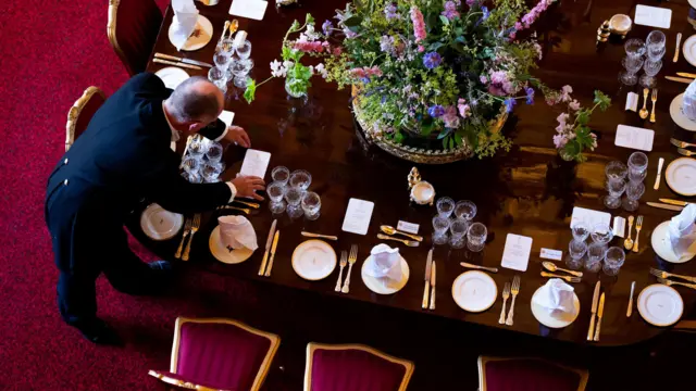 A man lays out cutlery on a banquet table