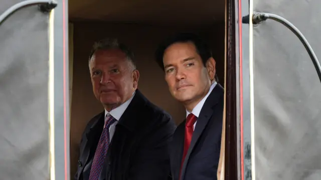Marco Rubio looks out the side of the carriage with Steve Witkoff sitting next to him