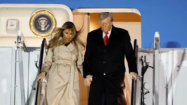 US first lady Melania Trump wearing a floor length Burberry trench coat steps out of Air Force One with husband US President Donald Trump