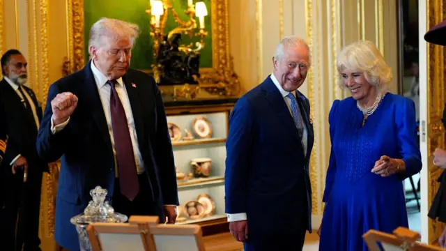 Donald Trump on the left, his fist raised while he looks at an archived collection. King Charles III and Camilla stood to the right, smiling.