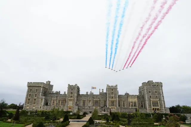 Wide shot of Windsor Castle as Red Arrows fly over from an eastward approach
